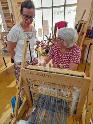 professeur de tissage expliquant à une élève devant un métier à tisser